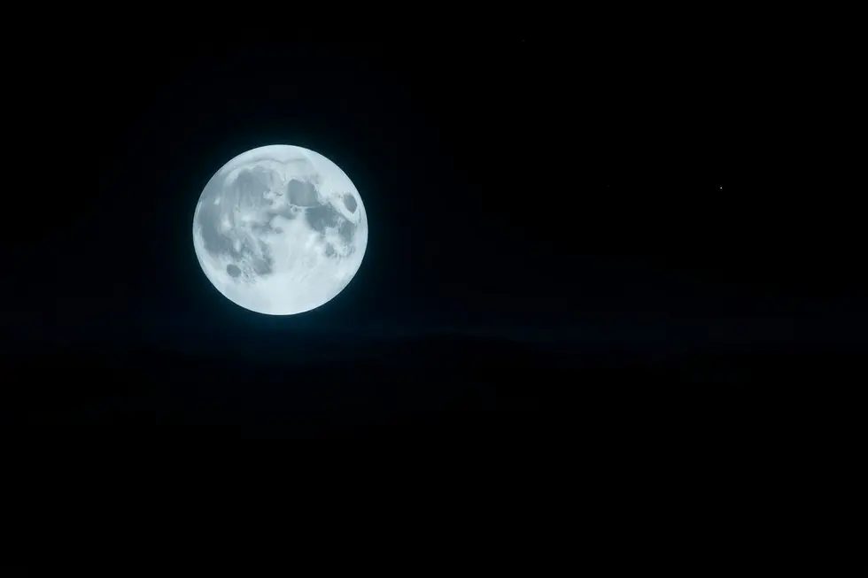 Uma visão da Lua cheia sobre um horizonte escuro.