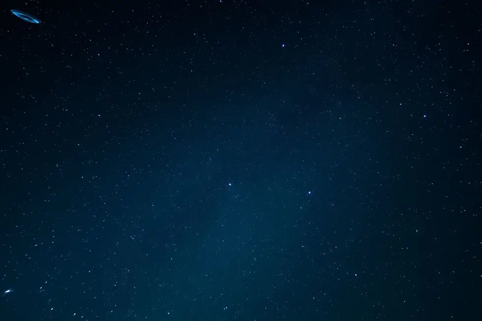 Vista ampla do céu noturno cheio de estrelas e OVNIs.