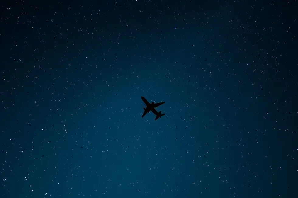 Céu estrelado com uma silhueta de avião.