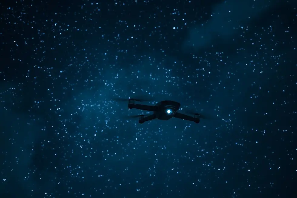 Imagem do céu noturno com um drone em voo.