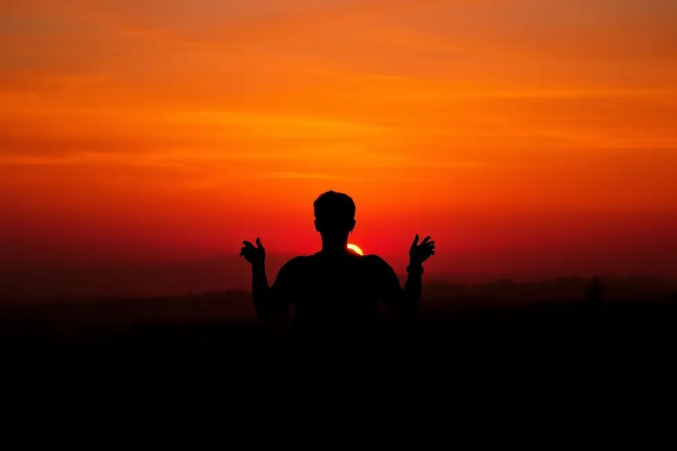 Pessoa admirando o pôr do sol e seus mistérios.