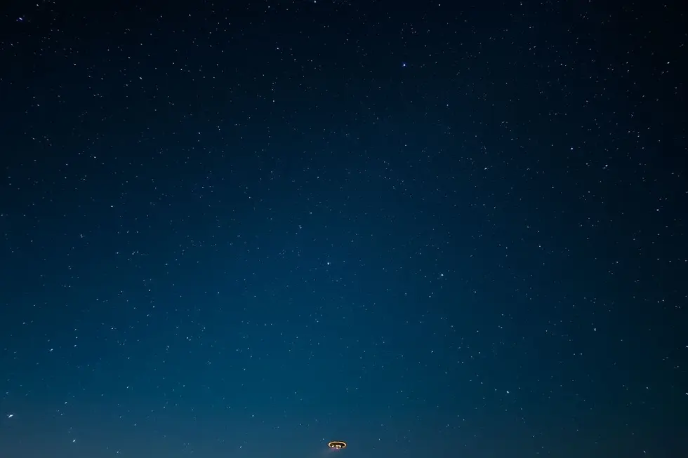 Céu noturno com estrelas e um UFO, representando os mistérios da ufologia.